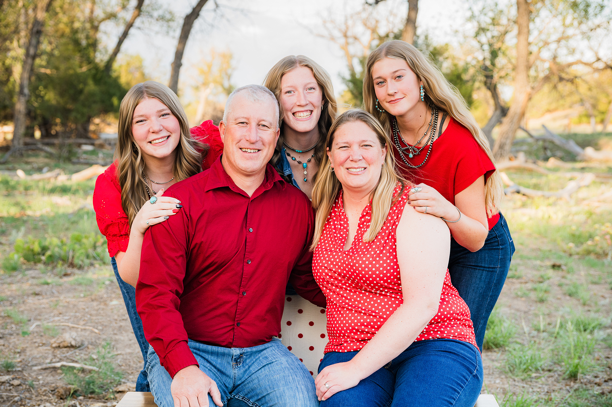 Two teenagers and one college student sisters pose with their parents in a field.