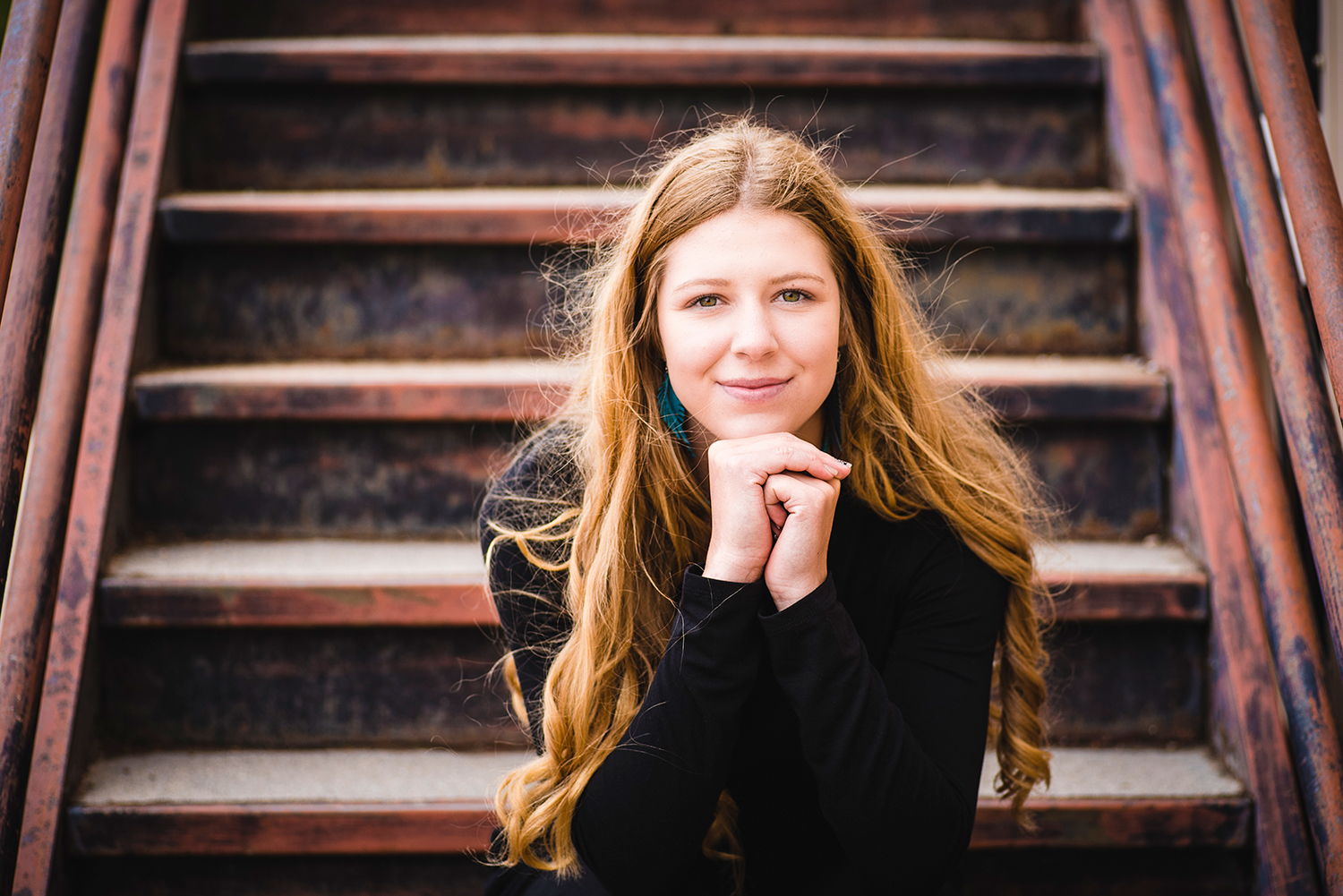 Teenage female dressed in a black sweater poses on a staircase in Yoder, Wyoming.